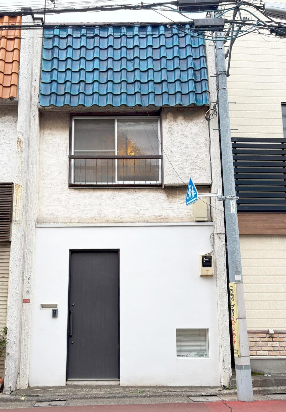 The Go Banana townhouse from the street — a slim Tokyo home with a blue tiled roof.