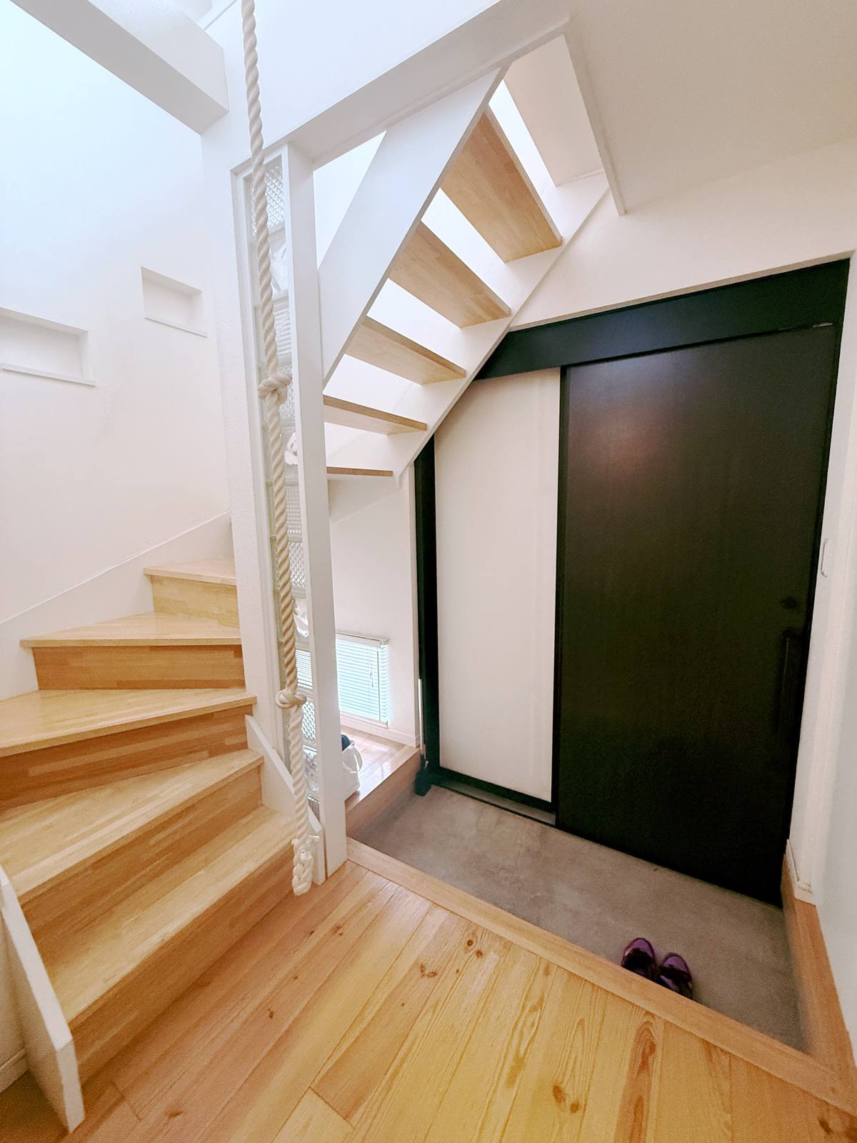 The wooden staircase with a climbing rope and the dark entrance door.