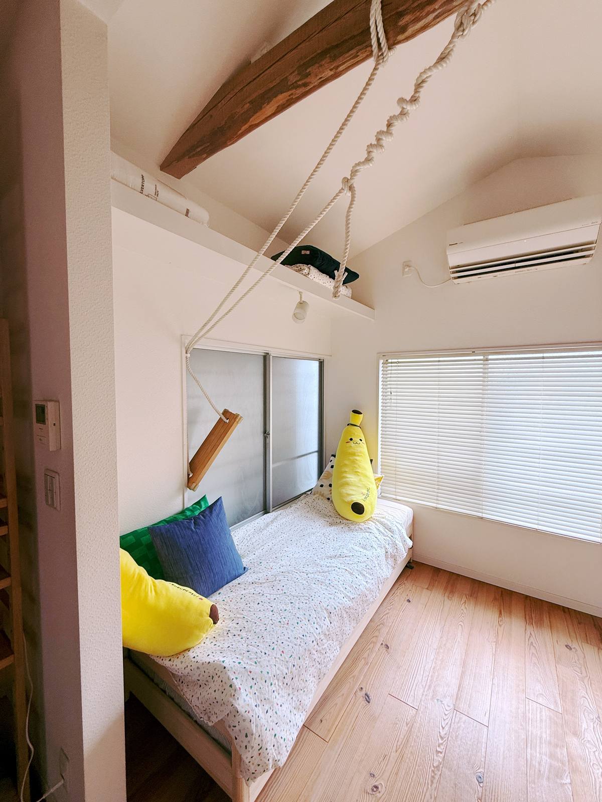 A wooden rope swing hanging beside the bed nook with banana plushies.