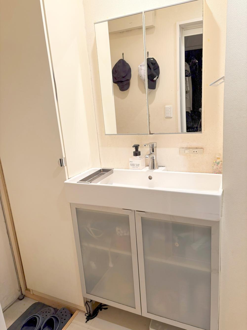 Washroom vanity with a wide sink and mirror cabinet.